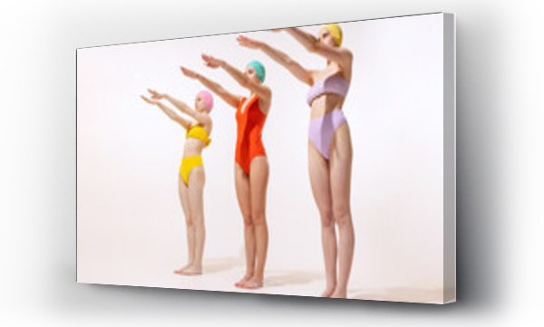 Wizualizacja Obrazu : #516357010 Portrait of three young women in vintage retro swimming suits posing isolated over grey studio background. Sportive lifestyle