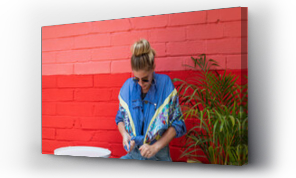 Wizualizacja Obrazu : #518421623 Young woman wearing a retro jacket sitting in front of a colorful wall