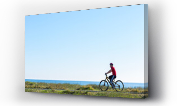 Wizualizacja Obrazu : #522764578 Teenage boy riding a bike on a seaside bike path