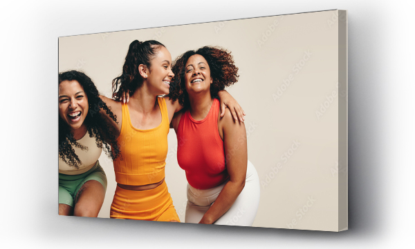 Wizualizacja Obrazu : #576971635 Fun in fitness clothing: Three female friends laughing happily in a sports studio