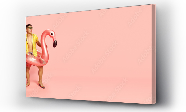 Wizualizacja Obrazu : #601404393 Banner with handsome young student, man wearing beach clothes standing with inflatable flamingo over pink background. Copy space for ad