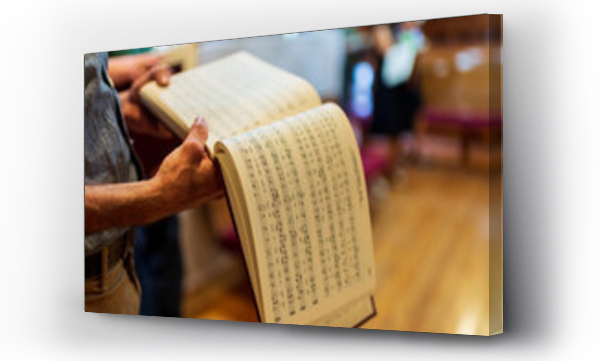Wizualizacja Obrazu : #613264993 A person holds a book of shape note songs in a church