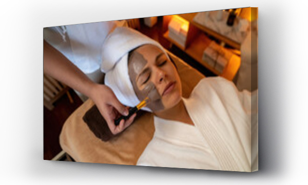 Wizualizacja Obrazu : #644210848 Serene ambiance of spa salon, woman customer indulges in rejuvenating with charcoal face cream massage with warm lighting candle. Facial skin treatment and beauty care concept. Quiescent