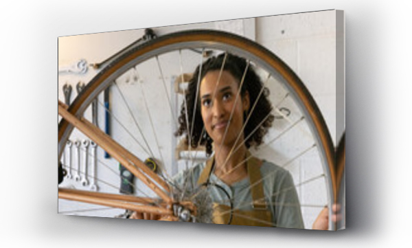 Wizualizacja Obrazu : #649666332 Young adult female repairing a bicycle in a bike store