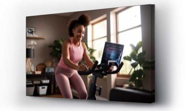 Wizualizacja Obrazu : #651816247 Young black woman during workout on a smart exercise bike at home. A scientific approach to training for maximum performance.