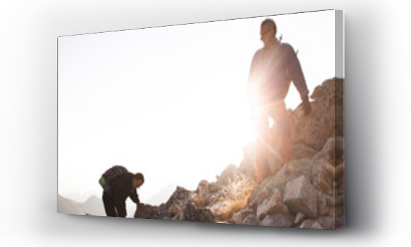 Wizualizacja Obrazu : #666448095 Friends climbing rocky mountain on sunny day