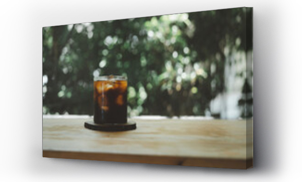 Wizualizacja Obrazu : #689496488 Cold black coffee with ice cubes on a wood table against nature background. Cold Brew. Summer drinks.