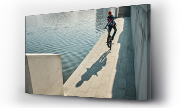 Wizualizacja Obrazu : #691373137 Man doing stunt with BMX bike near lake on embankment