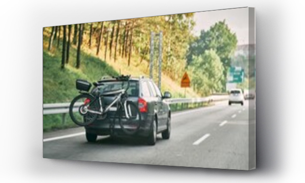 Wizualizacja Obrazu : #691877029 On the Road with Bikes. Car-mounted Trunk Bicycle Transport. Back view car with mounted bike tail carrier driving on highway road