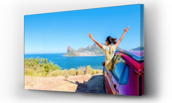 Wizualizacja Obrazu : #694262520 woman outside a car window with hands up, a car at Chapmans Peak Drive in Cape Town South Africa looking out over the ocean. women on a road trip at the garden route South Africa with a renal car