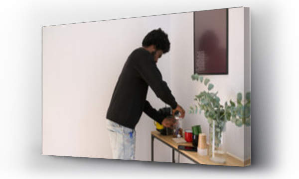 Wizualizacja Obrazu : #695208581 Morning Routine with Espresso. Black man preparing coffee in a serene home setting.