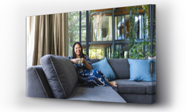 Wizualizacja Obrazu : #702577759 Portrait of happy asian woman on couch with mug of coffee at home