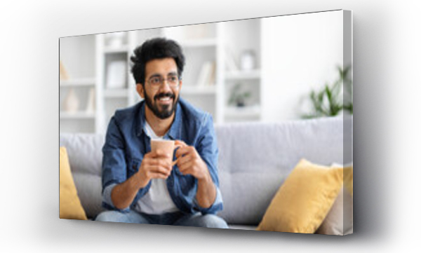 Wizualizacja Obrazu : #707616299 Joyful Indian man holding coffee cup with both hands and looking away