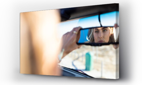 Wizualizacja Obrazu : #736736393 Young Caucasian woman adjusts the rearview mirror in a car on a road trip