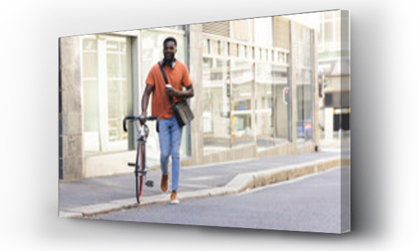 Wizualizacja Obrazu : #744775570 A young African American man walks with his bike outdoors in the city with copy space