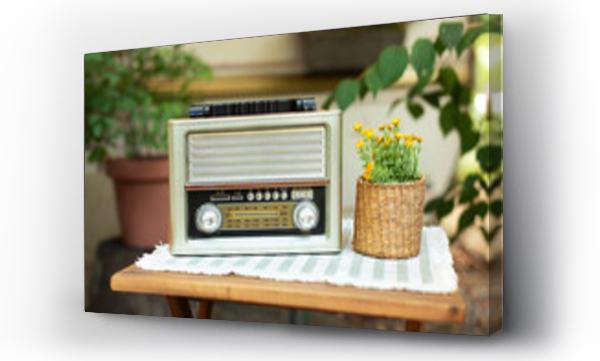Wizualizacja Obrazu : #827162901 The FM channel is playing music, a stylish retro radio player stands on a wooden table. Close up view of beautiful vintage radio and flowers in pot.	
